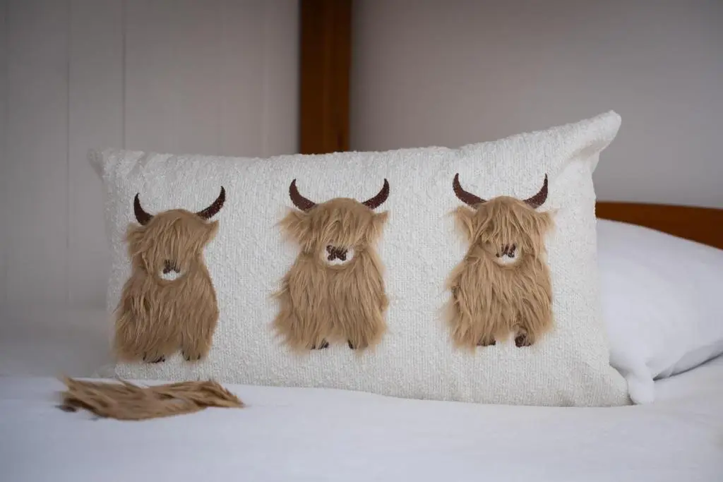 a pillow with three yak heads on a bed at Mabels Cottage by the beach in Nairn