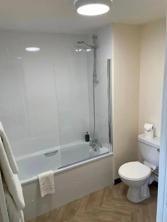 a bathroom with a tub and a toilet and a shower at Wick Bay Apartments in Wick