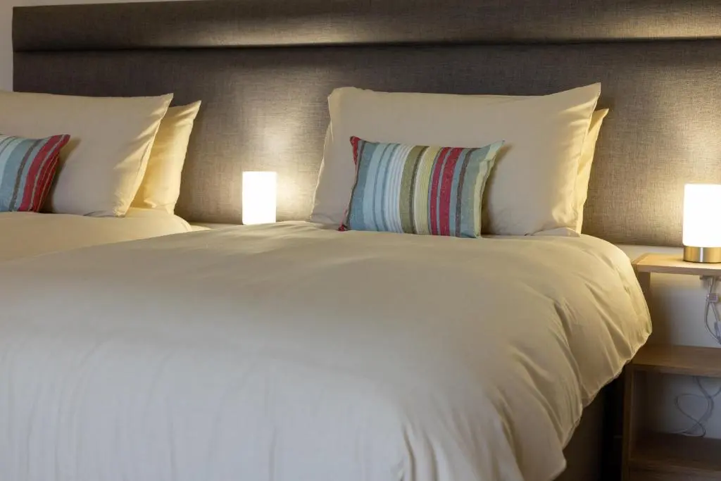 a large white bed with two pillows and two lamps at Wick Bay Apartments in Wick