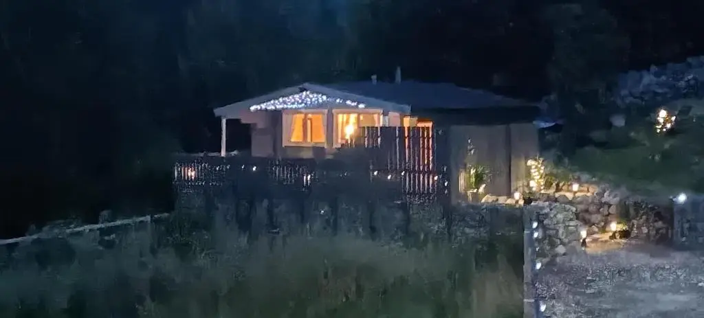 a house with a lit up window at night at Fairvine Cabin Fort Augustus Mtn View Pet Friendly in Fort Augustus