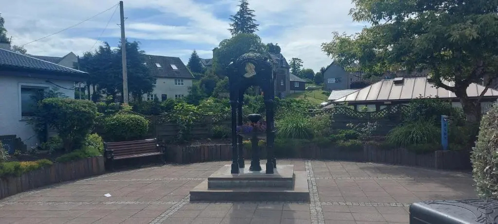 a statue of a clock in the middle of a courtyard at Fairvine Cabin Fort Augustus Mtn View Pet Friendly in Fort Augustus