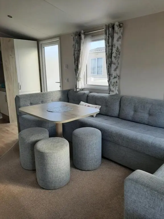 a living room with a couch and a table and stools at Swallows at Silversands in Lossiemouth