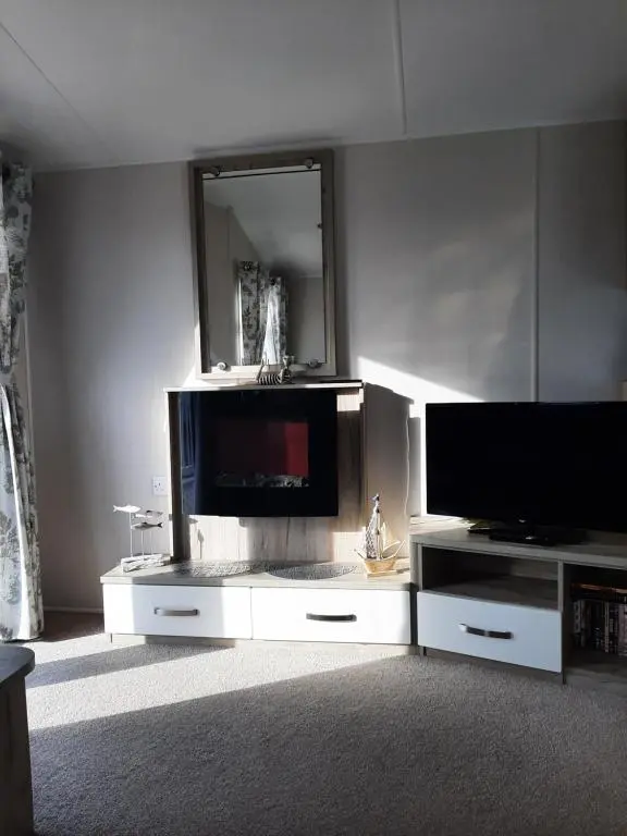 a living room with a tv on a white entertainment center at Swallows at Silversands in Lossiemouth
