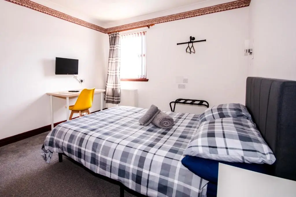 a bedroom with a bed and a desk and a chair at Weston House in Keith