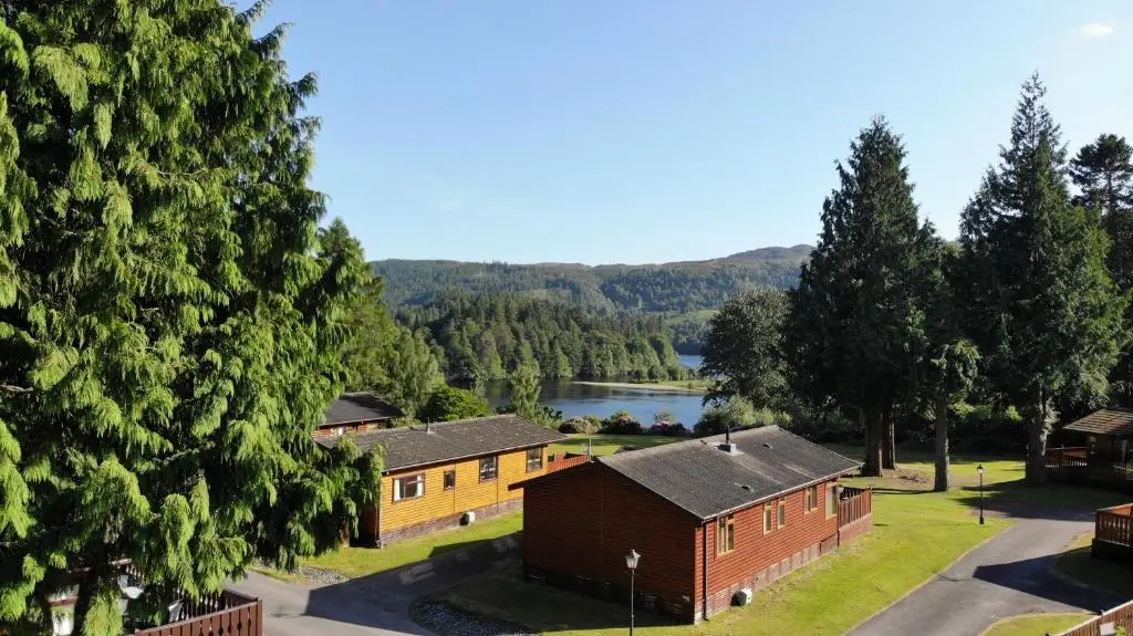 an aerial view of a house with a lake at Faskally Woods Holiday Park in Pitlochry