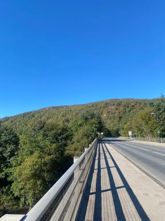 a bridge over a road with trees on the side at The mountain retreat in Aviemore