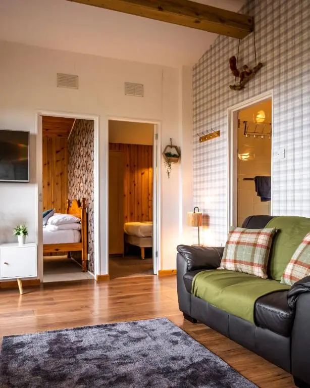 a living room with a couch and a bedroom at Ancarraig Lodges in Drumnadrochit