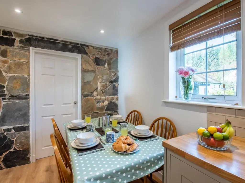 a dining room with a table and chairs and a stone wall at Holiday Home Jenkins Cottage by Interhome in Fort Augustus