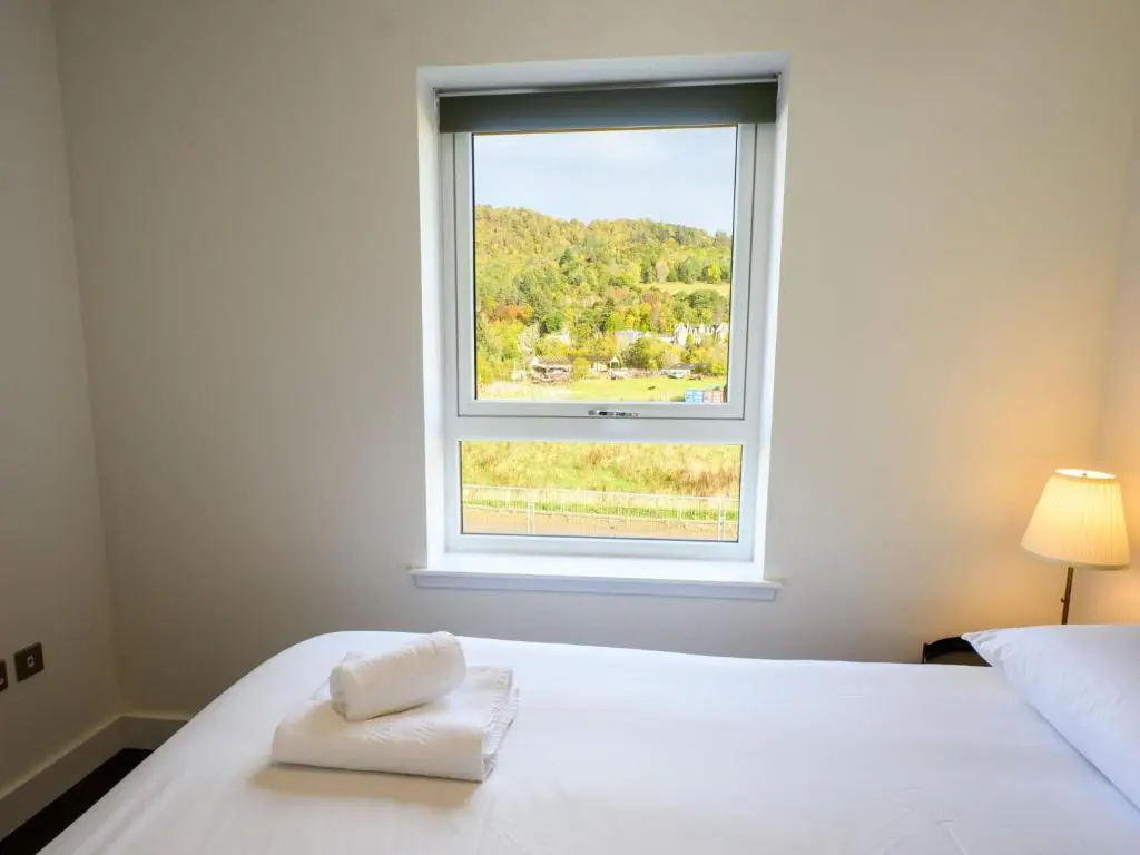 a bedroom with a white bed and a window at Apartment Craigmonie Apartment by Interhome in Drumnadrochit