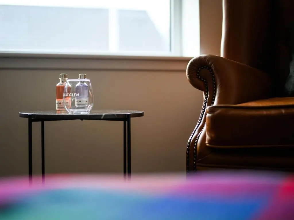 a table with two bottles on it next to a chair at Apartment Craigmonie Apartment by Interhome in Drumnadrochit