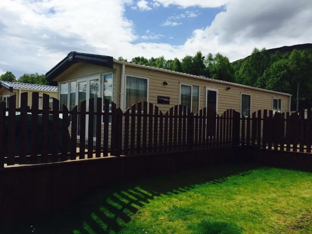 a wooden fence in front of a house at Aviemore holiday park No 39 in Aviemore