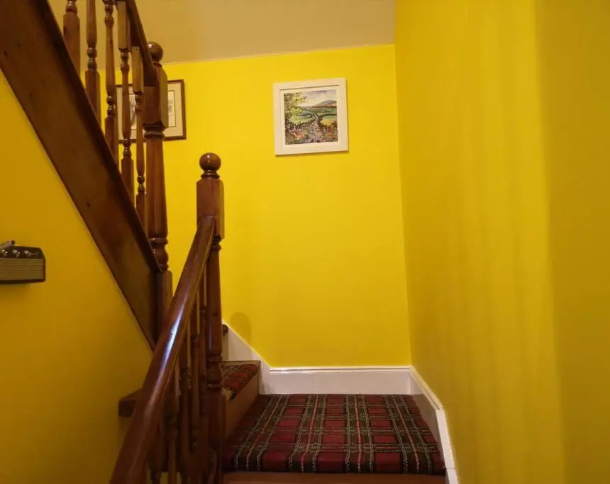 a yellow room with a staircase with yellow walls at Friars Shott Cottage in Inverness