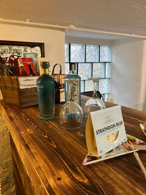 a counter with bottles and glasses and a box on it at The Urquhart in Oldmeldrum