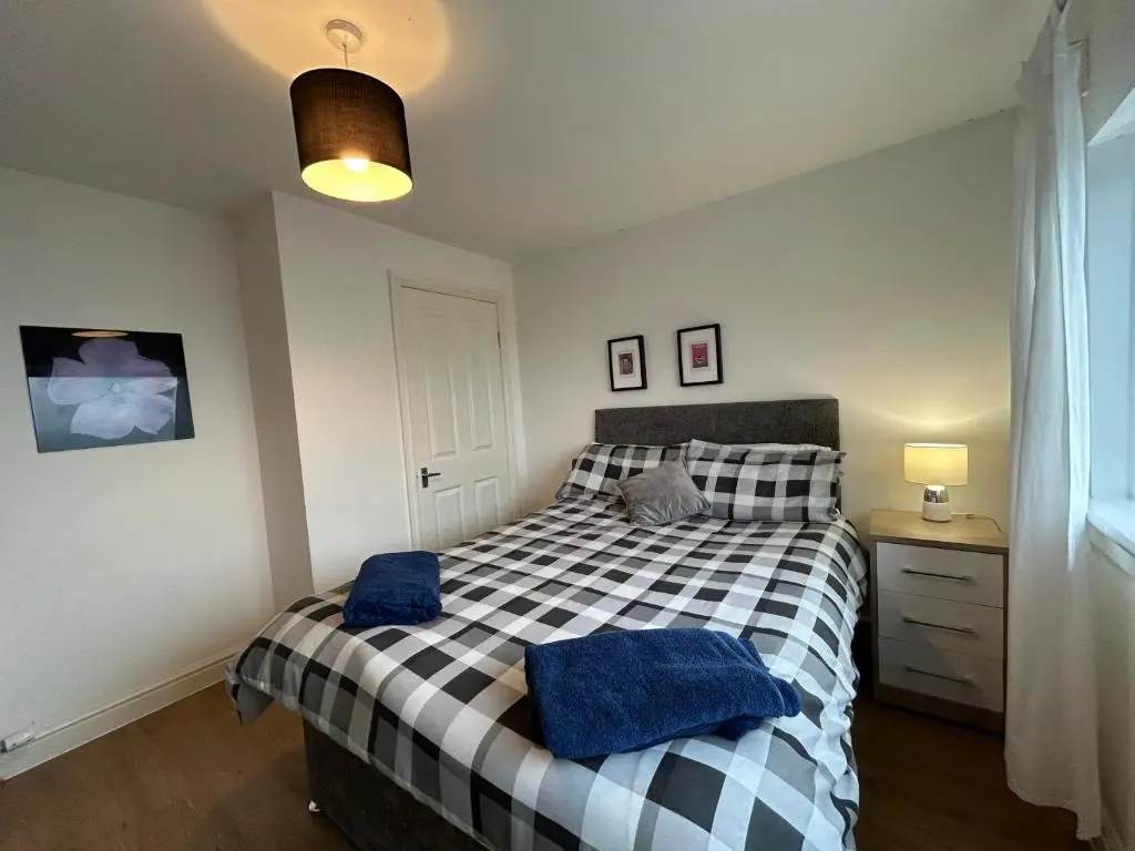 a bedroom with a bed with blue towels on it at Carley's House, Macduff in Macduff