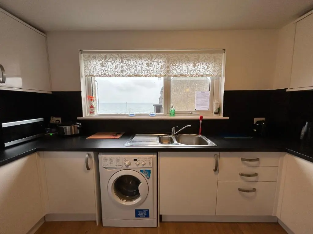 a kitchen with a sink and a washing machine at Carley's House, Macduff in Macduff