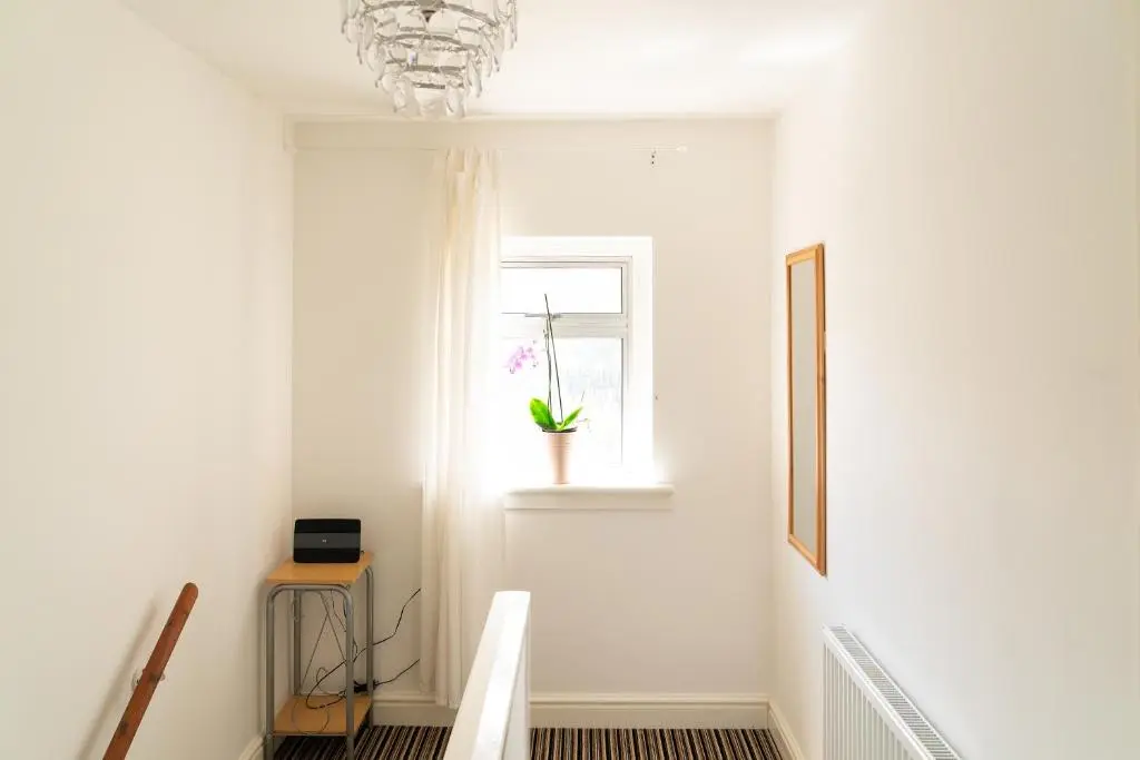 a white hallway with a window and a plant in a vase at Carley's House, Macduff in Macduff