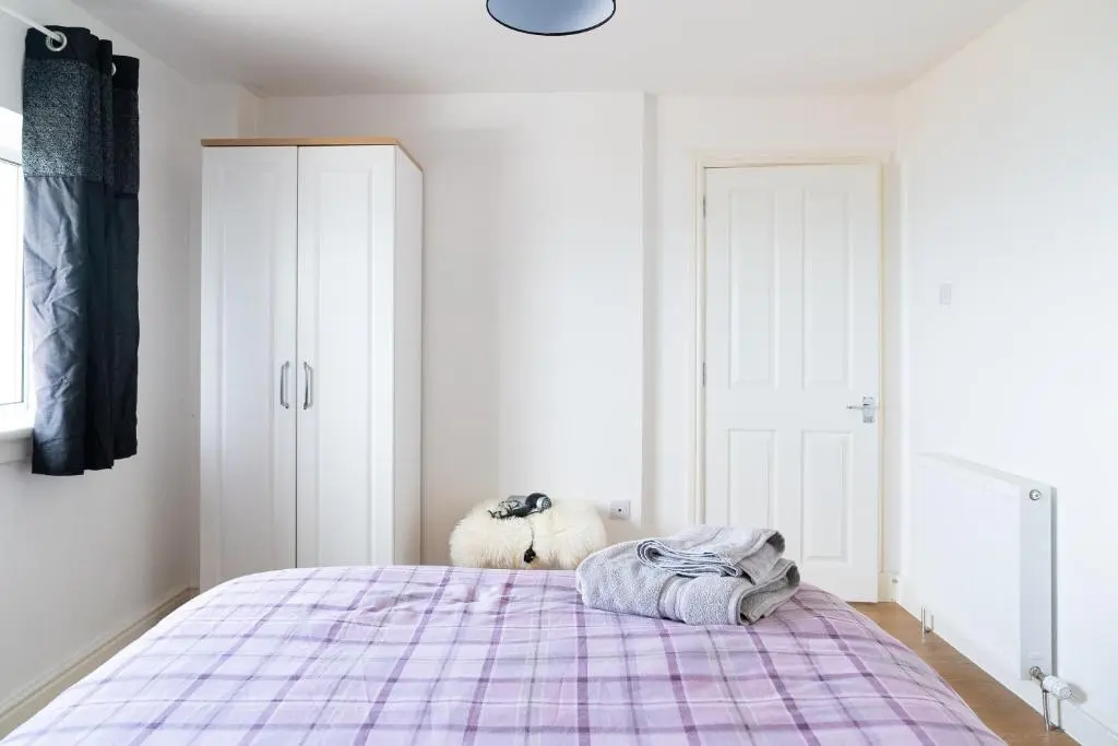 a bedroom with a bed with a purple blanket at Carley's House, Macduff in Macduff