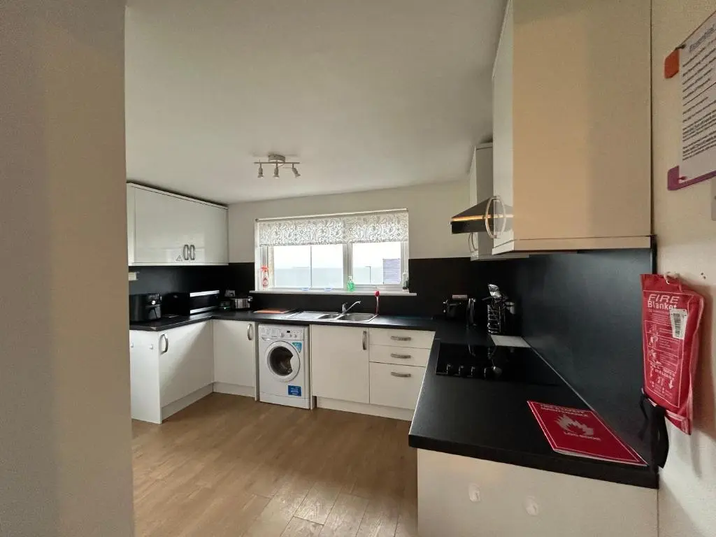 a kitchen with white cabinets and a washer and dryer at Carley's House, Macduff in Macduff