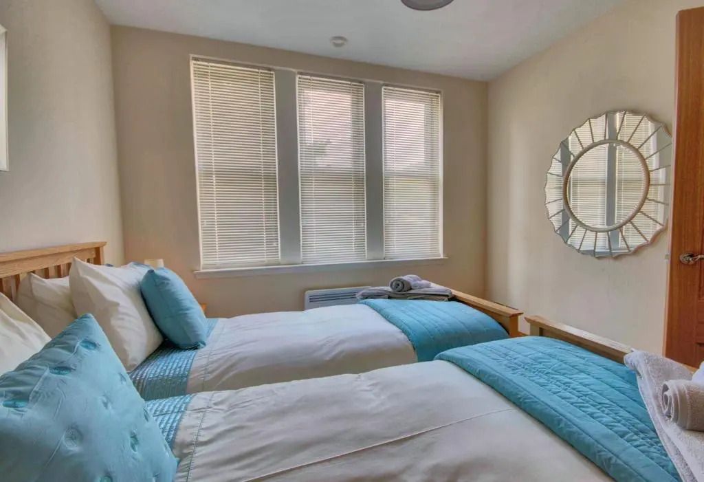a bedroom with two beds and a mirror at 1 Argyle Place, Dornoch in Dornoch