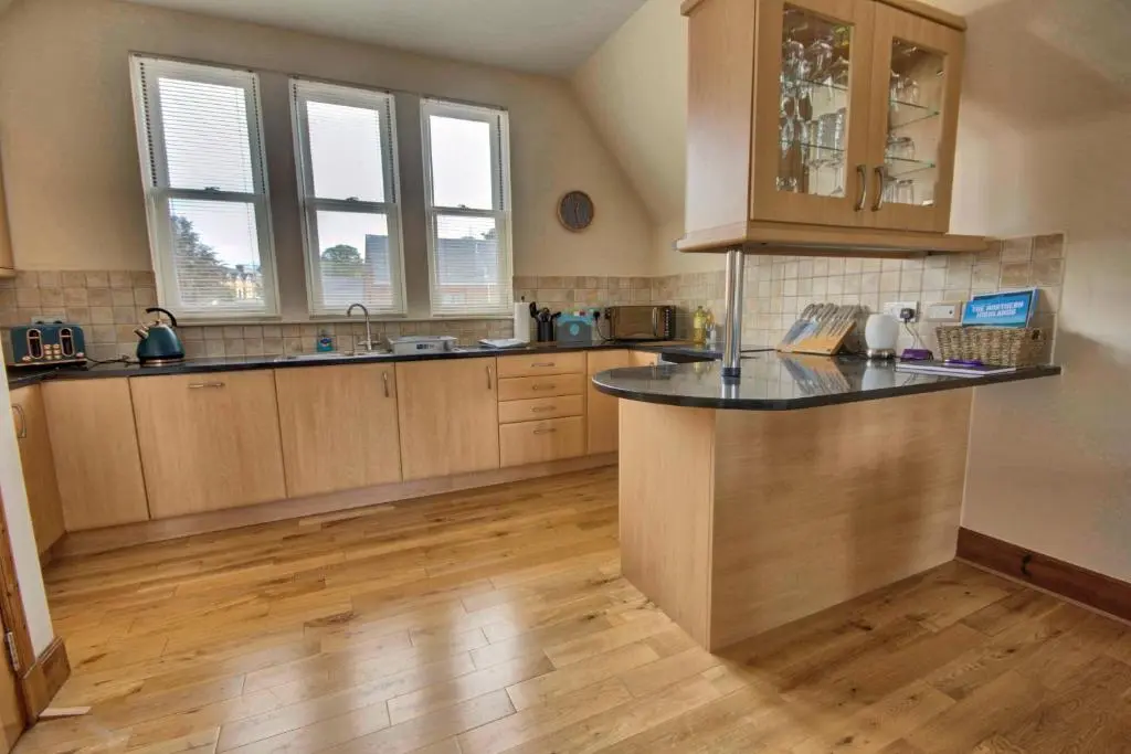 a kitchen with wooden cabinets and a counter top at 1 Argyle Place, Dornoch in Dornoch