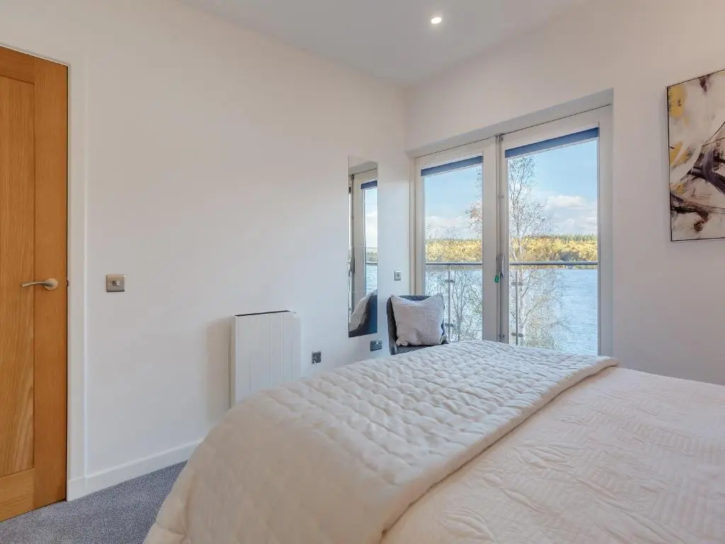 a bedroom with a large bed and a large window at Kimcraigan Lodge in Lochend
