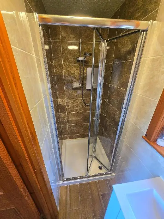 a shower with a glass door in a bathroom at Luichart Lodge in Lochluichart Station