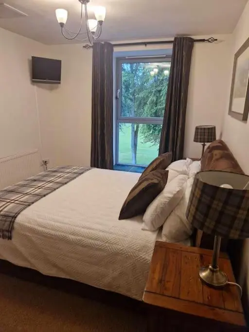 a bedroom with a large bed and a window at Glen Mor in Fort Augustus