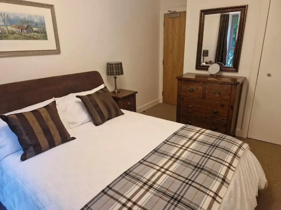 a bedroom with a bed and a dresser and a mirror at Glen Mor in Fort Augustus