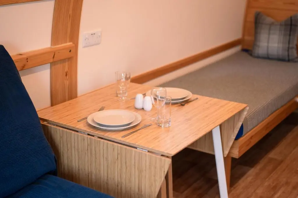 a small wooden table with plates and glasses on it at The Loft by Wigwam Holidays in Kinloss