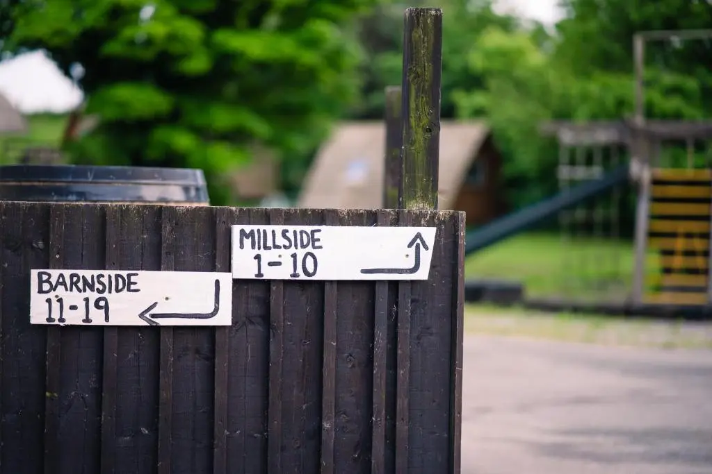 a wooden fence with street signs on it at The Loft by Wigwam Holidays in Kinloss