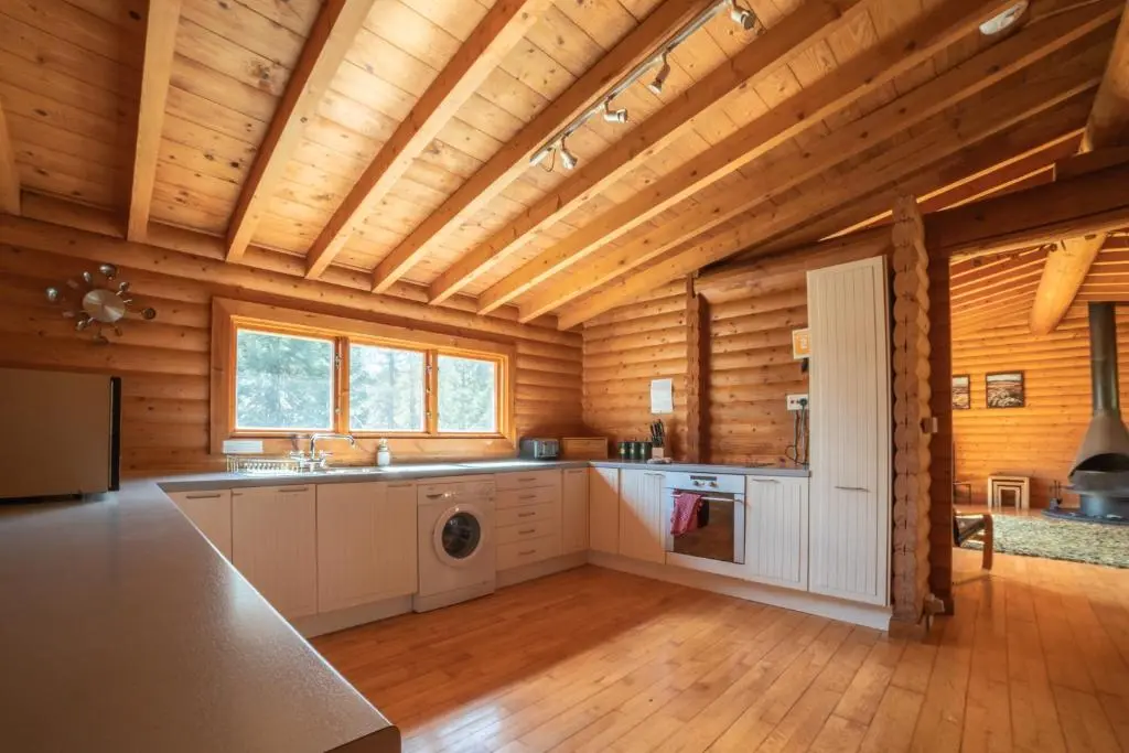 a kitchen in a log cabin with a washer at Our Log House in the woods in Balnald