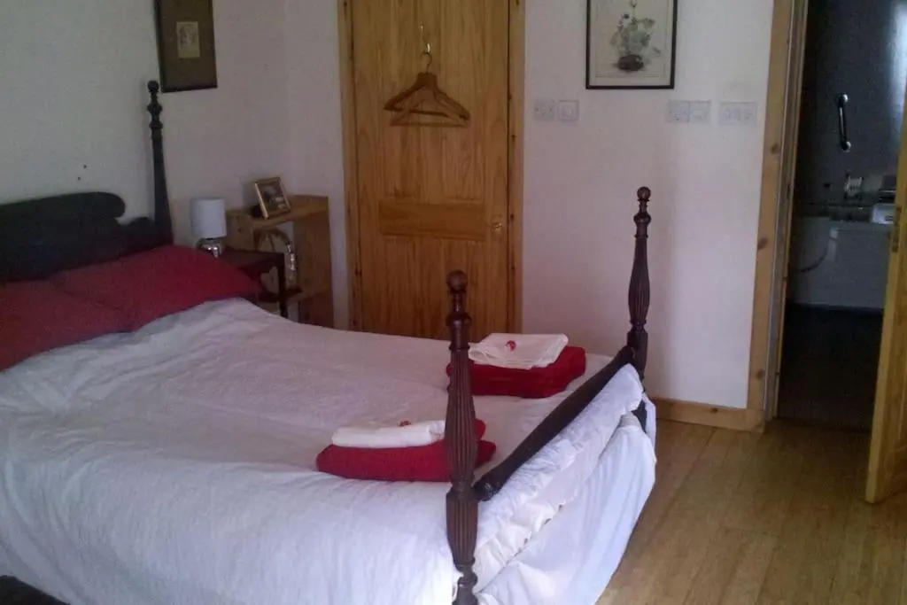 a bedroom with a bed with red and white blankets at Taigh Sona easy access apartment with double bed in Ullapool