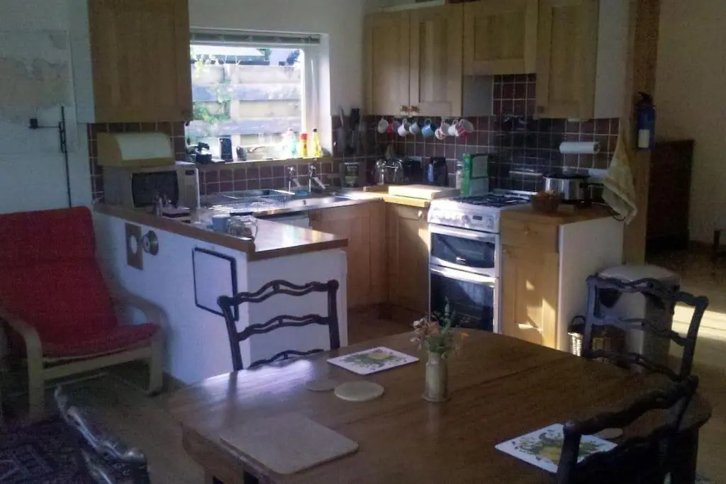 a kitchen with a wooden table and a stove top oven at Taigh Sona easy access apartment with double bed in Ullapool