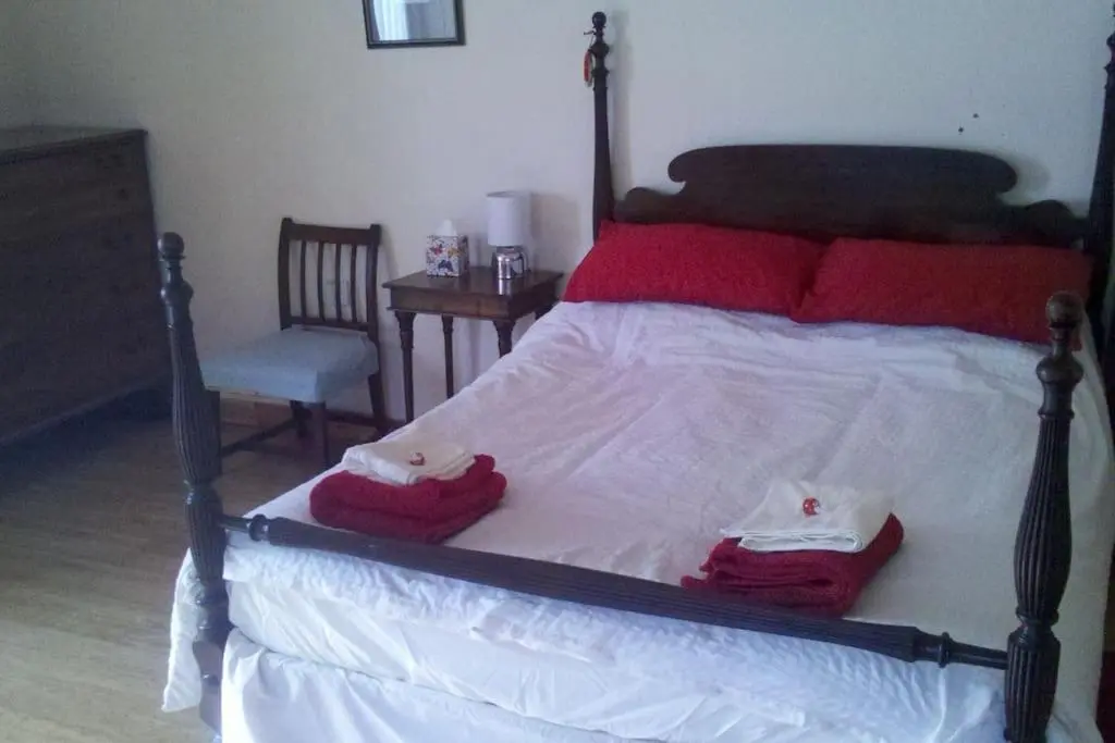 a bedroom with a bed with red pillows and a chair at Taigh Sona easy access apartment with double bed in Ullapool