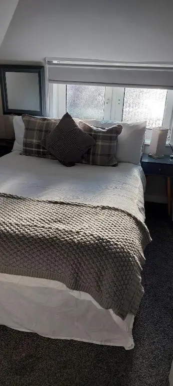 a bedroom with a large bed with pillows and a window at Riverbank Guesthouse Inverness in Inverness