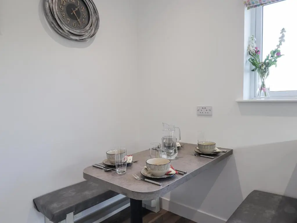 a table with plates and glasses and a clock on the wall at Avemar in Buckie