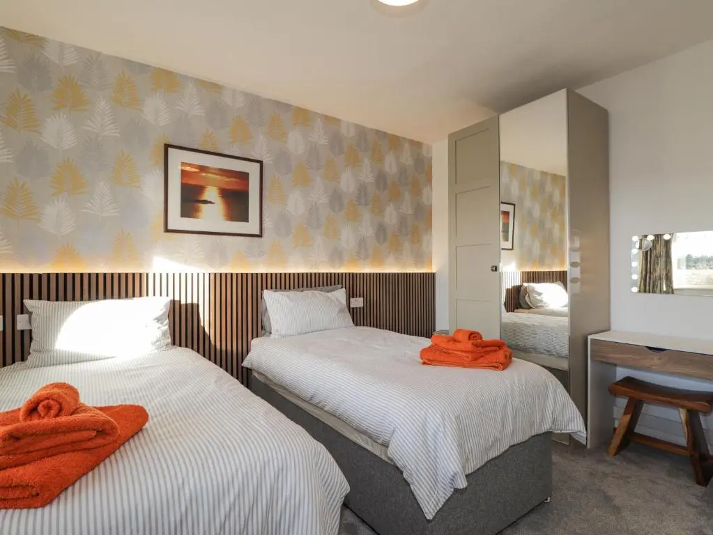 a bedroom with two beds with orange towels on them at Avemar in Buckie