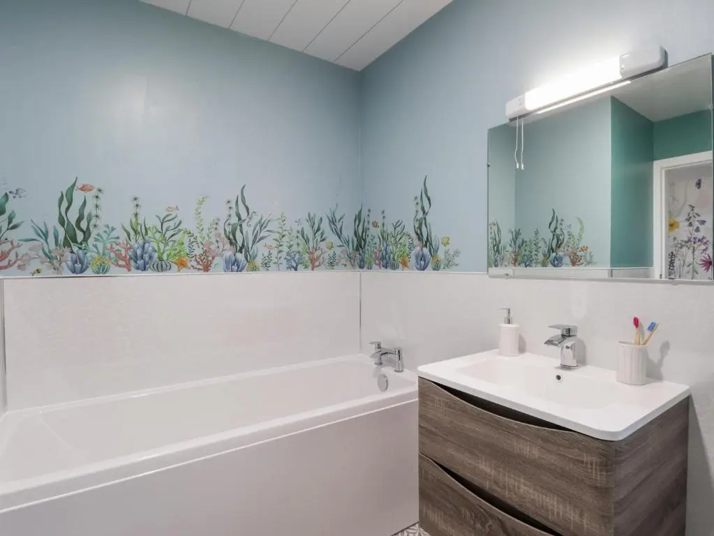 a bathroom with a tub and a sink and a mirror at Avemar in Buckie