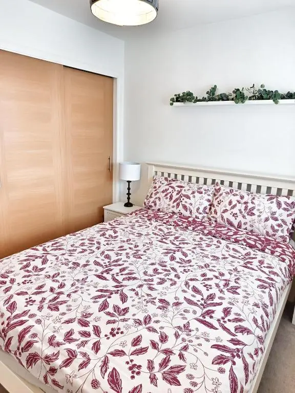 a bedroom with a bed with a red and white comforter at 4 miles to Westhill by Lains Lettings in Aberdeen