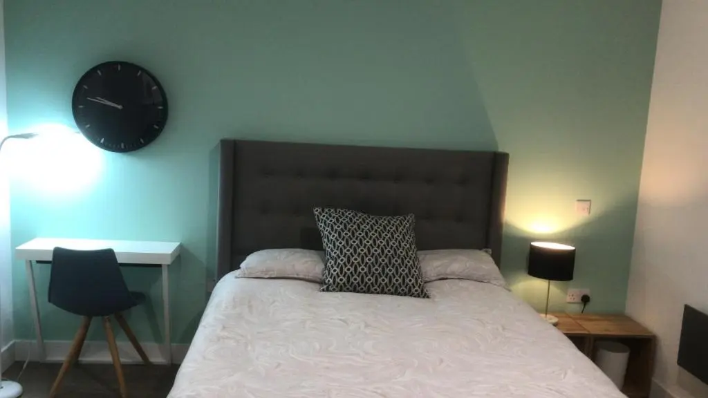 a bedroom with a bed with a clock on the wall at Elgin Studios in Elgin