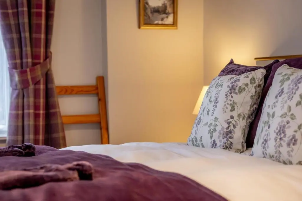 a bedroom with a bed with pillows and a window at Falls Cottage in Glenlivet