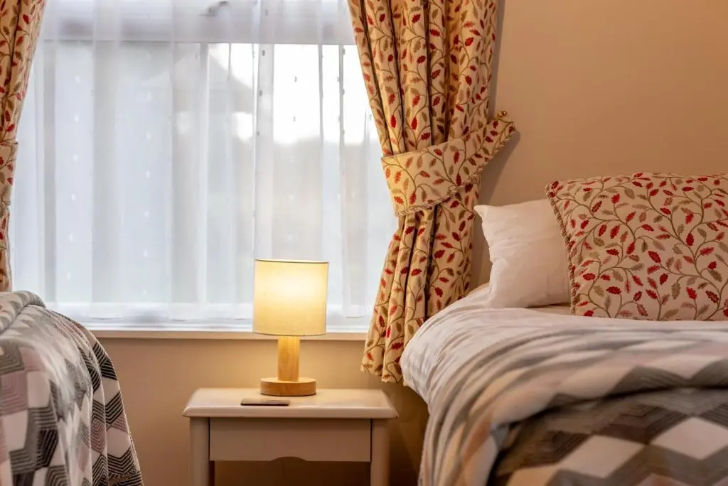 a bedroom with a bed and a window with a lamp at Falls Cottage in Glenlivet