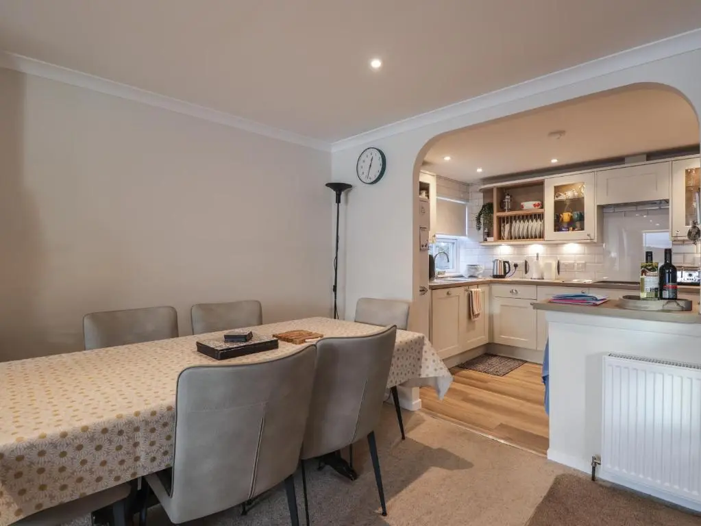 a dining room with a table and a kitchen at Bayside Cottage in Forres