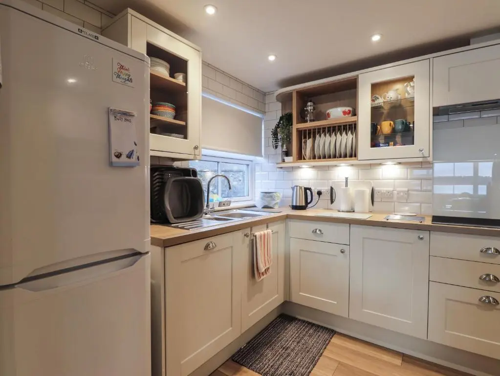 a kitchen with white cabinets and a white refrigerator at Bayside Cottage in Forres