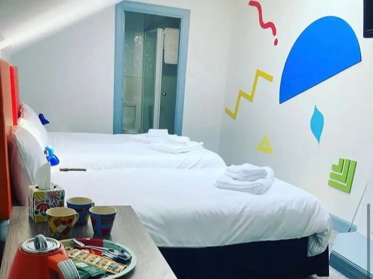 a room with two beds and a table with a plate of food at Friars Bridge Guesthouse in Inverness
