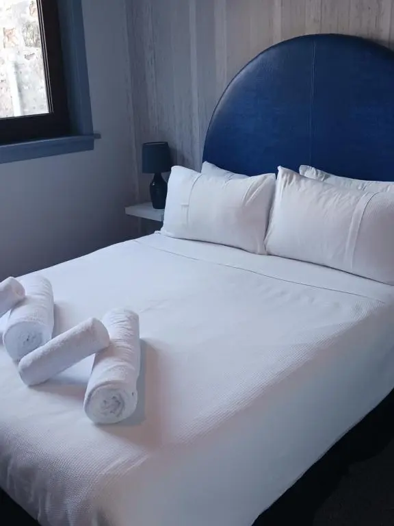 a white bed with two rolled towels on it at Friars Bridge Guesthouse in Inverness