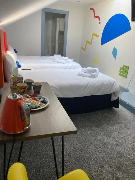 a hotel room with two beds and a table with a table at Friars Bridge Guesthouse in Inverness