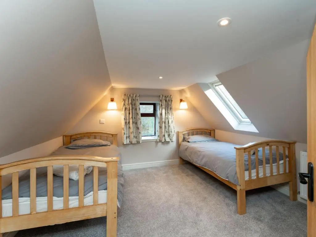 two beds in a attic bedroom with two windows at Holiday Home Rose Cottage by Interhome in Farr