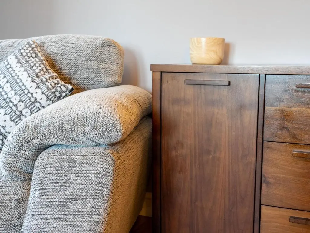 a couch next to a wooden cabinet with a pillow at Holiday Home Rose Cottage by Interhome in Farr