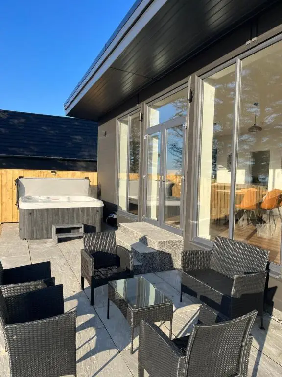 a patio with a tub and chairs and a pool at Thrumster Lodges - 3 Luxurious Self Catering Lodges on the NC500, 2 with Hot Tubs in Wick